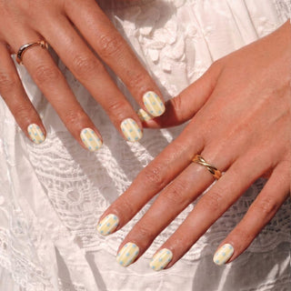 Hand displaying Sweet Disposition press on nails with retro pastel stripes and baby blue polka dots for a sunny summer aesthetic.