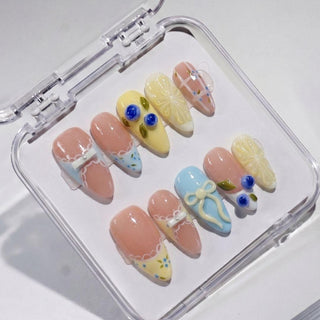 The EyeCandys Sweet n Tart Press-On Nails set features decorative handmade pastel nails with 3D bows, plaid, flowers, and lace designs, all arranged neatly in a transparent case.