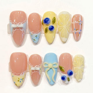 The EyeCandys Sweet n Tart Press-On Nails are handmade with pastel designs, 3D bows, blue flowers, scalloped edges, and plaid patterns in soft pink, yellow, blue, and white tones.