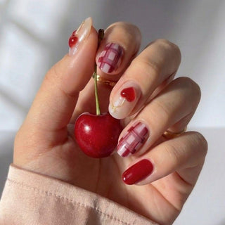 Hand displaying Very Cherry press on nails with fuchsia tones, 3D cherry motifs, and sleek metallic accents for a fun summer manicure.