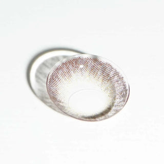 A single EyeCandys Pink Label Vintage Grey contact lens with a pixelated pattern is displayed on a white surface, casting a soft shadow nearby.