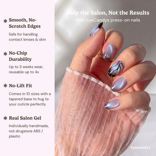 A hand with glossy, purple EyeCandys Wing Woman Press-On Nails featuring black and white abstract designs and a silver butterfly charm holds sheer pink fabric. Enjoy smooth edges, no-chip durability, secure fit, and real salon gel quality.