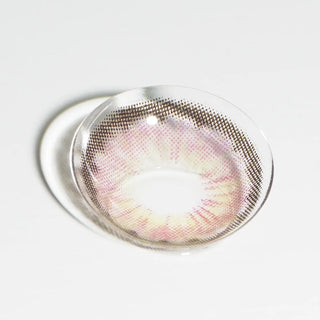 A single EyeCandys Pink Label Angel Pink contact lens, featuring a translucent brown and pink circle lens design, rests on a white surface with a subtle shadow.