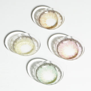 Four natural color contact lenses, including EyeCandys Pink Label Angel Green, are arranged on a white surface, with the green lens casting a distinct shadow.