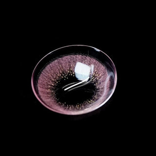 A close-up of EyeCandys Attitude Glitter Pink contacts (1 PAIR) by EyeCandys, featuring a black dotted pattern on pink and high water content, placed on a black background with light reflections highlighting their natural look.