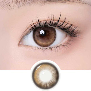 A close-up shows an eye with long lashes wearing i-Girl One Pick Becca Azuki Brown contacts by i-Girl. Below, the colored lens is displayed clearly on a white background.