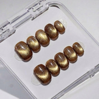 EyeCandys Diet Cola press on nails featuring deep warm brown cat-eye nails with gold micro shimmer and glossy finish in a short round shape.
