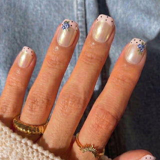 Hand wearing Eyecandys Berry French press-on nails with a glossy pearlescent nude base, pastel pink French manicure, blueberry accents, and a short square shape.