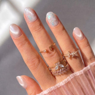 Hand wearing Eyecandys Champagne Toast press-on nails with a warm peach champagne cat-eye finish, glossy shine, and salon-quality short oval shape.