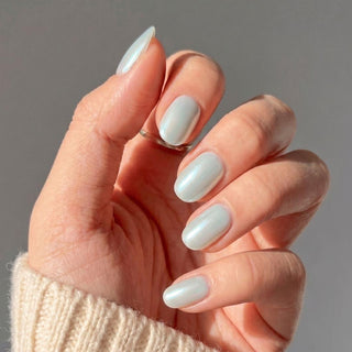 Hand wearing Eyecandys Peritinkle press-on nails with a luminous periwinkle chrome finish, glazed effect, and salon-quality short oval shape.