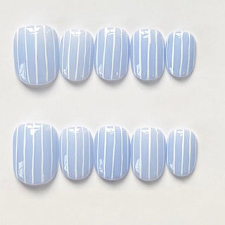 Short round press on nails EyeCandys Pinstripes with periwinkle blue base and clean white vertical stripe nail art for a minimalist look.