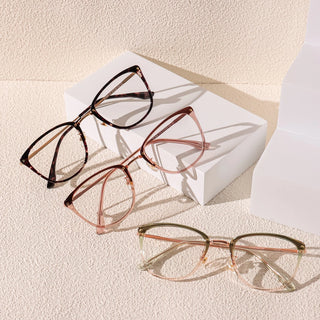 Three pairs of EyeCandys Posh Square unisex rectangular glasses in brown tortoiseshell, light pink, and gold are showcased on a textured beige surface with a white block in soft natural light.