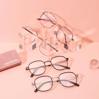 Four pairs of EyeCandys fashion glasses, including the Stunner Square frame, are arranged on clear acrylic blocks and a pink surface with a matching EyeCandys case and glass sphere, all set against a pink background.