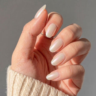 Hand wearing Eyecandys Soft Serve press-on nails with a luminous pearl white chrome finish, glazed effect, and salon-quality short oval shape.