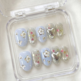 EyeCandys Fleur de Slay press on nails with soft blue base, multicolour confetti glitter, and sculpted silver floral nail art design.