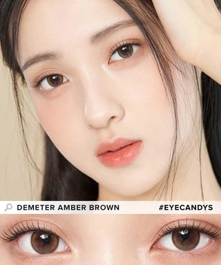 A close-up of a woman with flawless skin and soft, peach-toned lips highlights her natural makeup and brown eyes enhanced by Gemhour Demeter 1-Day 13.5 Amber Brown contacts (10pk). A detailed view shows both eyes wearing these daily disposables.
