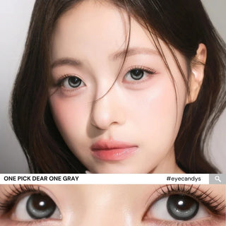 Model wearing i-Girl One Pick Dear One Grey contact lenses from EyeCandys, featuring cool grey iris color, weighted non-rotating design, subtle eye-widening effect, and all-day comfort with silicone hydrogel