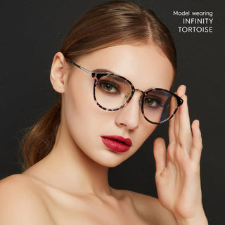 A woman with slicked-back hair and bold red lipstick wears the EyeCandys Infinity Oversized Oval tortoiseshell eyeglasses. One hand is near her face, with “Model wearing EyeCandys Infinity Oversized Oval” text in the top right corner.