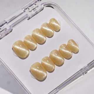 EyeCandys Lemon Drops press on nails featuring warm golden yellow cat-eye nails with pearlescent shimmer and glossy glass-like finish in a short round shape.
