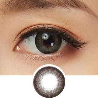 A close-up of an eye wearing NEO Vision Extra Dali Grey by NEO Vision, framed by long lashes and natural makeup, with a round insert below displaying the grey circle lens design in detail.