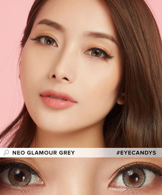 A close-up of a woman with long brown hair wearing NEO Vision Glamour Grey (Custom Toric for Astigmatism) contacts by NEO Vision. Her natural makeup and peach lips highlight her grey lenses. Text: "NEO Vision Glamour Grey" and "#EYECANDYS".
