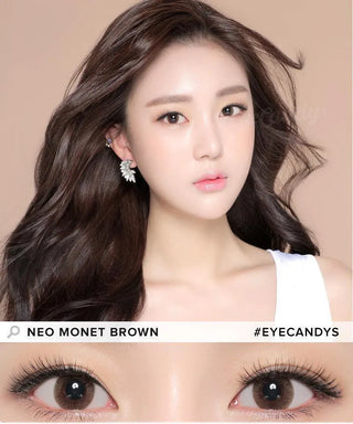 A woman with long, wavy brown hair and dewy makeup wears NEO Vision Monet Brown (Custom Toric for Astigmatism) lenses. The close-up highlights her eyes, labeled "NEO MONET BROWN" and "#EYECANDYS"—ideal for a natural look with circle lenses.