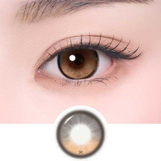 i-Sha Reborn Oak Haze color contact lens on top of a dark eye paired with subtle eye makeup and curled wispy eyelashes, above the contact lens design.
