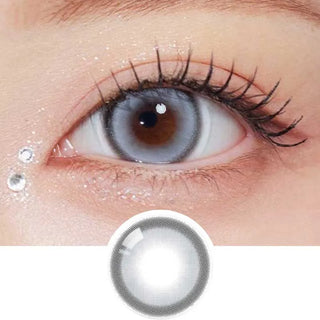 A close-up shows an eye wearing Olola Glint 1-Day Grey (10pk) daily lenses by Olola, accented with subtle glitter and two rhinestones at the outer corner. Below the eye, a single grey contact lens is displayed.