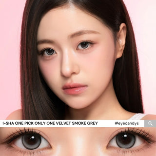 A young woman with long straight dark hair poses against a pink backdrop, wearing natural makeup and i-Sha One Pick Only One 1-Day Velvet Smoke Grey (10pk) contacts. A close-up reveals their 3-tone gradient effect. Text: “i-Sha ONE PICK ONLY ONE VELVET SMOKE GREY.”.