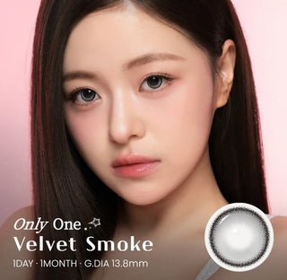 A woman with smooth, straight hair wears natural-looking colored contacts in a subtle smoke grey shade. Text reads: i-Sha One Pick Only One Velvet Smoke Grey, 1 Day, 1 Month, G. DIA 13.8mm. A close-up image of a grey contact lens from i-Sha appears in the lower right corner.