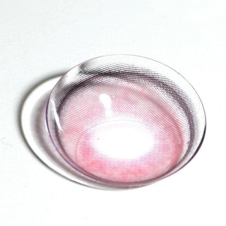 A close-up of the EyeCandys Powerglow Reddish Pink color contact lens by EyeCandys, featuring a pink and black dotted pattern, displayed on a white surface with a faint shadow.