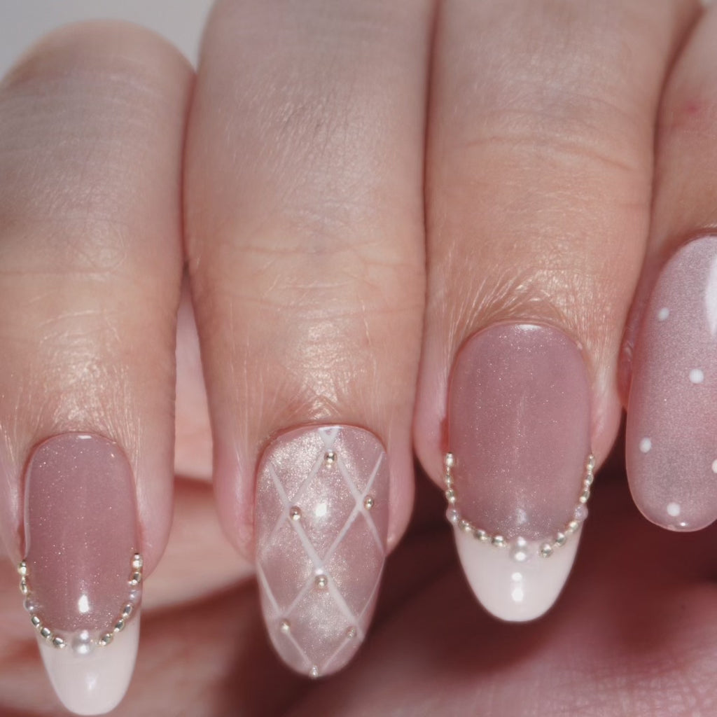 Hand wearing EyeCandys Ballet Slippers press-on nails in glossy nude ballet pink with quilted details and pearl accents