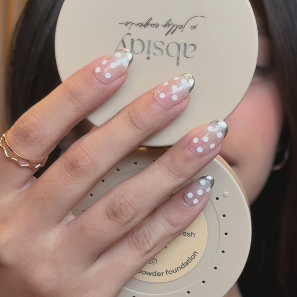 Hand wearing EyeCandys Silver Spotted press-on nails featuring a stylish silver spotted design for a chic and eye-catching manicure look.