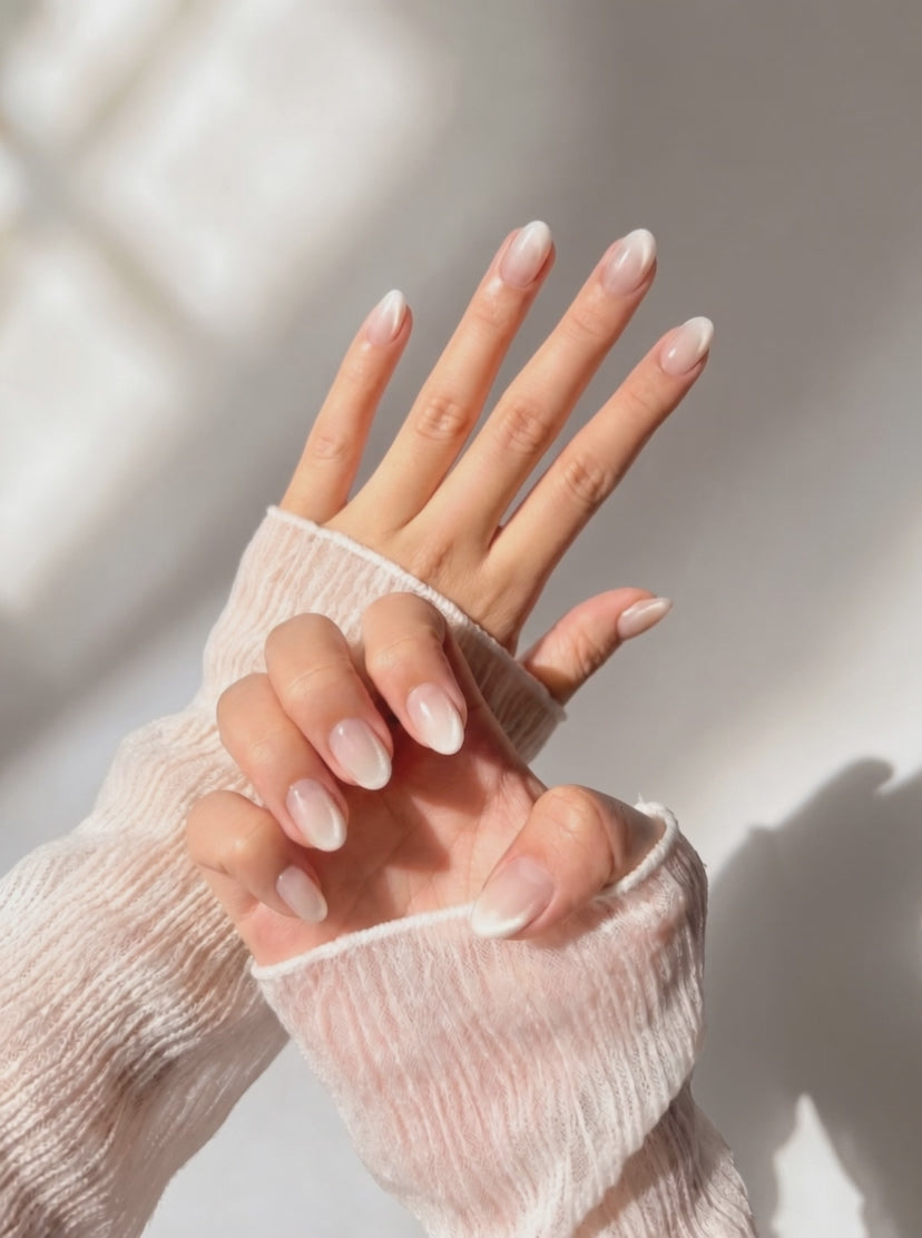 Hands wearing Eyecandys Seraphina press on nails, soft blush pink cat-eye finish with pearl shimmer on short oval nails, creating an elegant luminous look