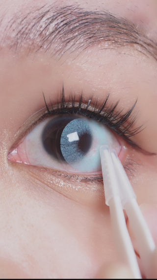 EyeCandys Dare to be Blue contact lens sliding onto an eyeball with a dark iris of an Asian model