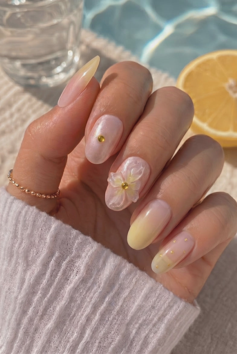 Wearing EyeCandys Daisy Does It Press-On Nails, sheer peach base melting into buttery yellow tips with pearl shimmer in an oval shape