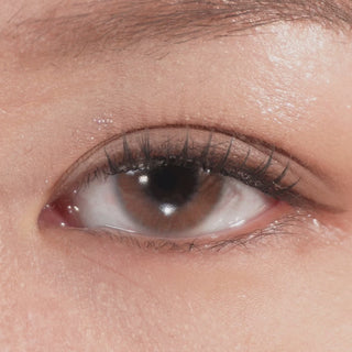 Close up of eye with long eyelashes blinking, wearing Eyecandys Aura Brown Grey prescription colored contact lenses for a natural enhanced look