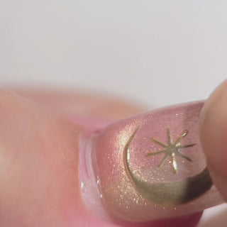 Close-up of EyeCandys Star Script press-on nails featuring multicolored sunset cat-eye nails with gold star nail art