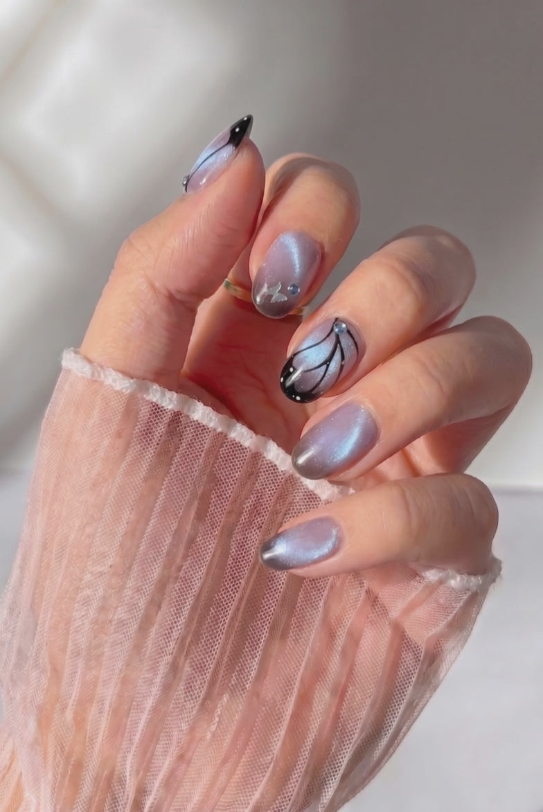 Wearing EyeCandys Wing Woman Press-On Nails, dusty mauve base fading into a smoky black tip with witchy fairycore details in an oval shape