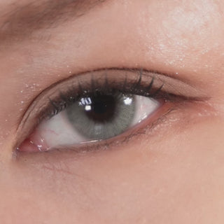 Close-up of an eye blinking while wearing EyeCandys Cadet Grey contact lenses, highlighting the natural grey tone and detailed lens pattern.