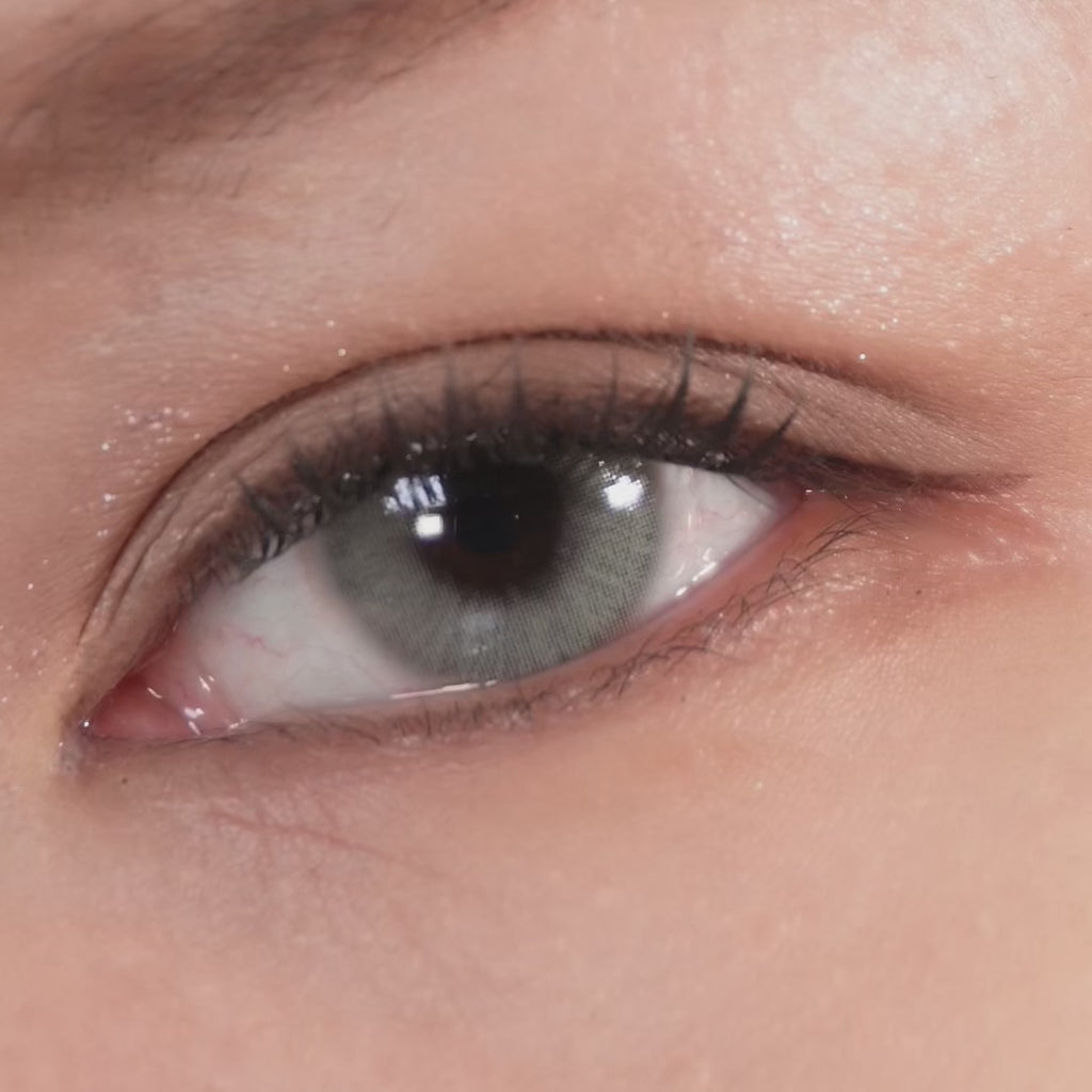 Close-up of an eye blinking while wearing EyeCandys Cadet Grey contact lenses, highlighting the natural grey tone and detailed lens pattern.