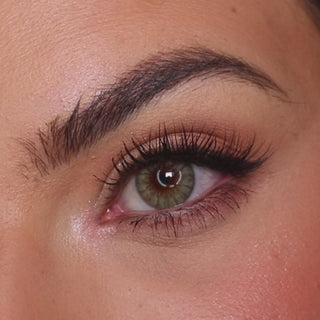 Model wearing EyeCandys Desire Lush Green colored contact lenses, showcasing a vibrant green eye transformation with close-up views, natural movement, and a fresh, vivid effect on brown eyes.