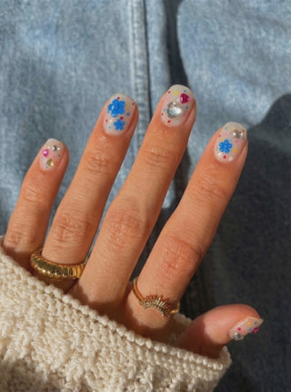 Wearing EyeCandys Dot Cake Press-On Nails, milky sheer base with scattered confetti dots in pink, blue, yellow, and red in a short round shape