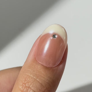Hand wearing EyeCandys Front Row press-on nails with sheer nude base, cat-eye French tips, and crystal accents