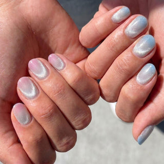 Hand wearing reusable First Light press on nails featuring pink to blue aurora gradient with luminous gold shimmer effect.