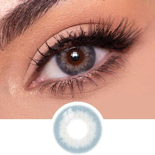 Close-up view of EyeCandys Sugarlook Blue contact lens on a model's dark eye, paired with natural eye makeup, above the graphic design of the blue eye contacts.