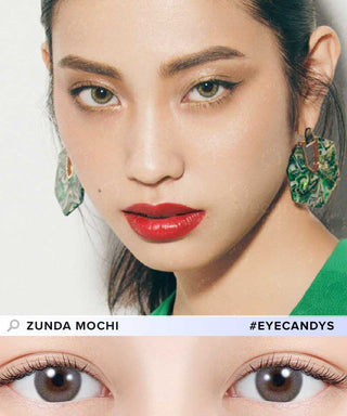 Close-up of a woman wearing N's Collection Zunda Mochi Green contacts—her green eyes stand out with bold red lipstick, winged eyeliner, green earrings, and matching outfit. Below: light brown eyes. Text: "Zunda Mochi" and "#EYECANDYS.